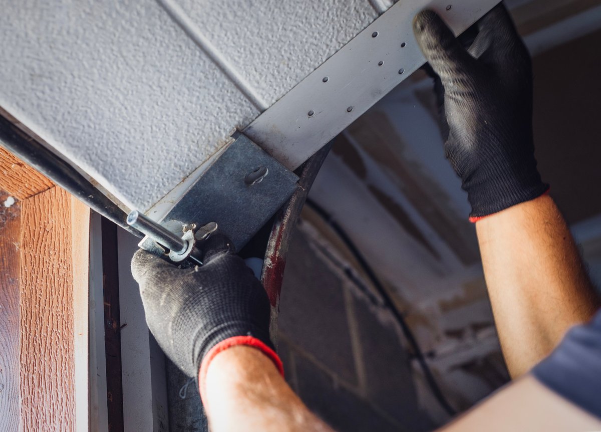Close-up of a worker attaching rollers to metal tracks during installation or repair
