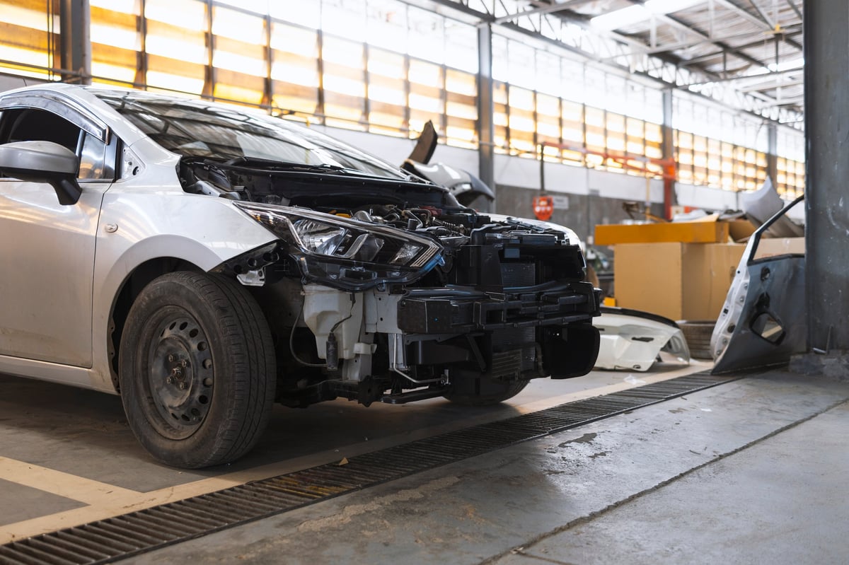 Damaged car in an auto repair garage with removed bumper after a collision
